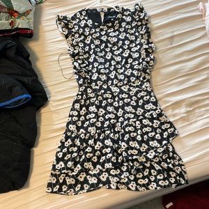This is a dress with a white daisy pattern on a black background. Knee length.